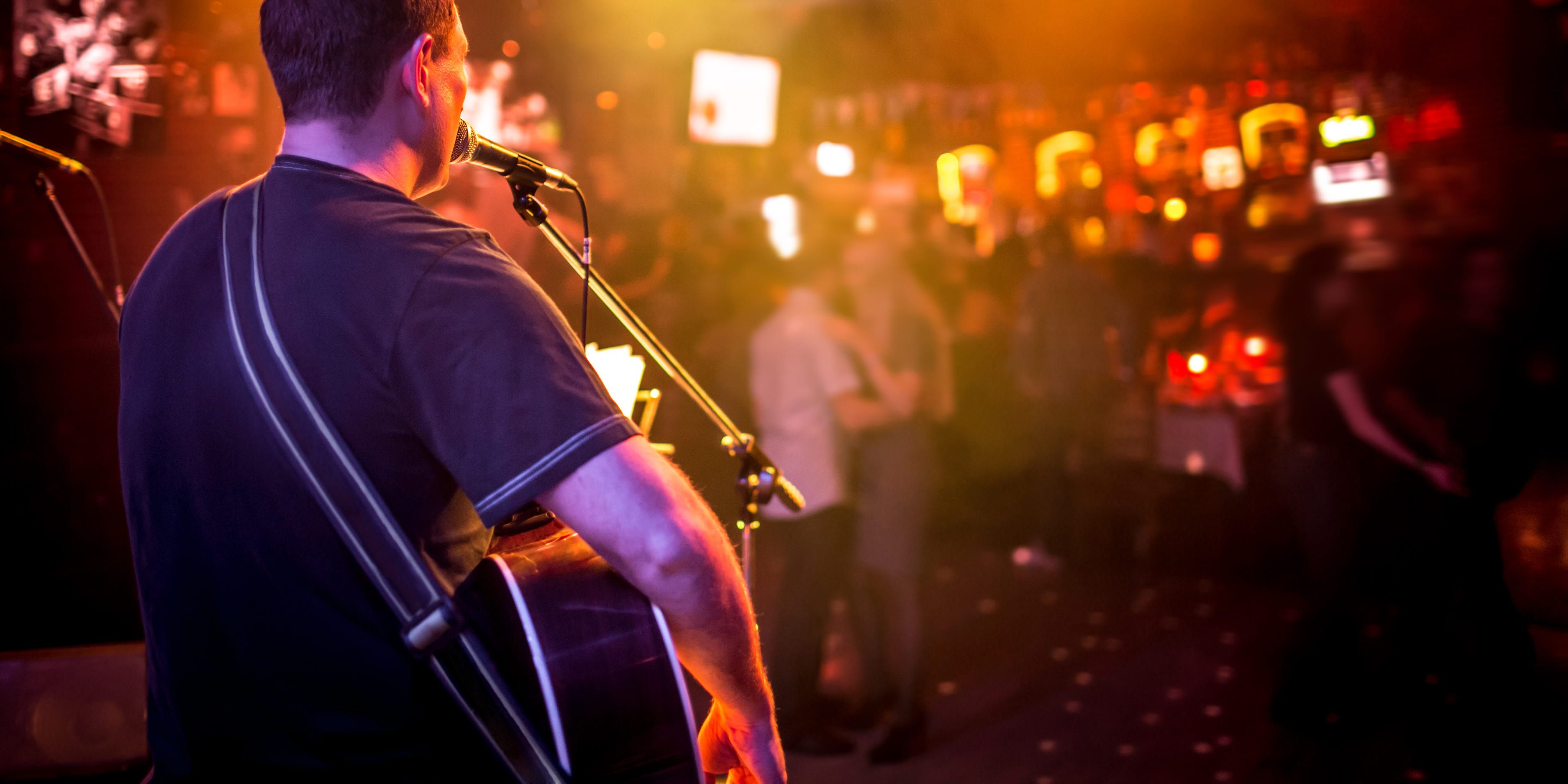 Persom singing and playing the guitar on stage