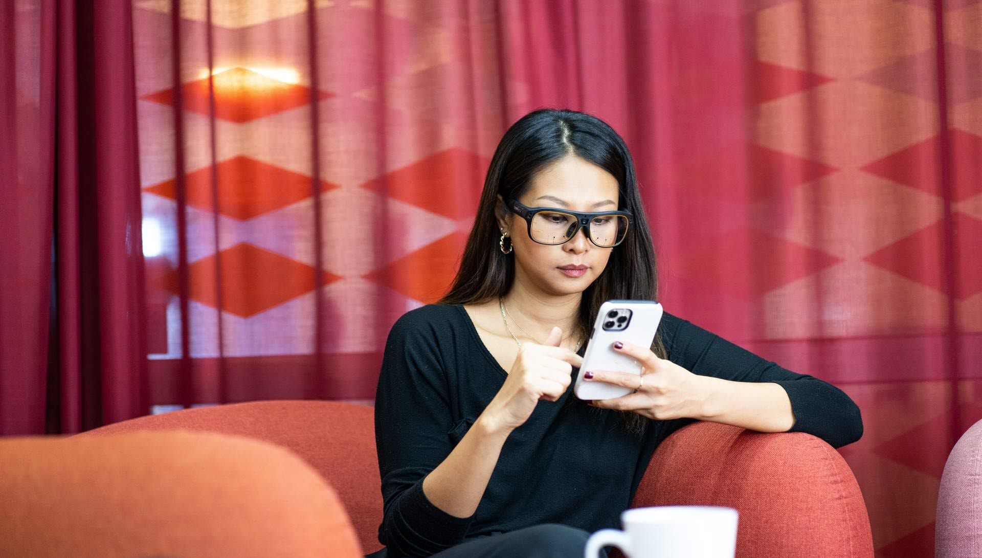 Woman using Tobii Pro Glasses 3 looking at mobile phone