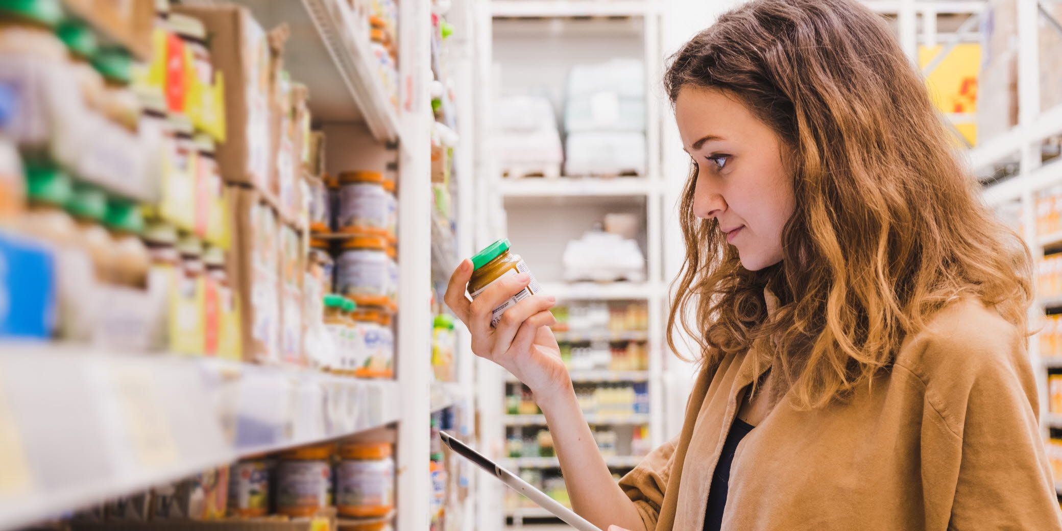 Woman looking at a baby food jar in the supermarket